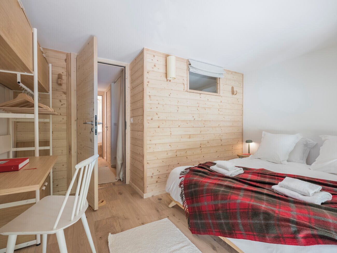 A bedroom with a bed, a desk, a chair, and a wardrobe.