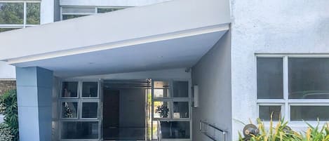 A modern building with a flat facade, large windows, and a covered entrance area.
