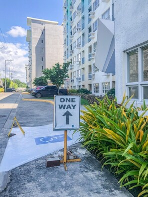A parking area with a 'ONE WAY' sign, a handicapped parking space, and a building with multiple floors and balconies. - Seawind Condominium - Davao City (Davao City)