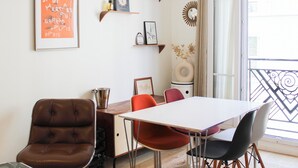 A dining area with a table, chairs, and a bookshelf. - Montmartre, Place du Tertre · Quiet & Bright (Paris)