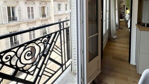 A balcony with a view of a building, a door leading to an interior space, and a glimpse of a kitchen area. - Montmartre, Place du Tertre · Quiet & Bright (Paris)