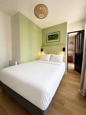 Ein Schlafzimmer mit einem großen Bett, einer Wandleuchte und einem Gemälde.