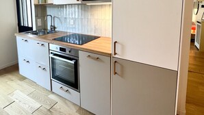 A modern kitchen with a built-in oven, a microwave, and a sink. - Montmartre, Place du Tertre · Quiet & Bright (Paris)