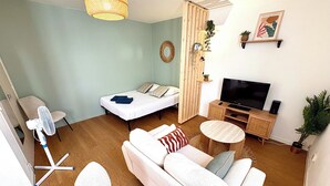 Uma sala de estar moderna com sofá, cama, televisão e uma mesinha.