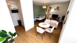 Um espaço compacto com área de refeições, sofá, televisão e cama.