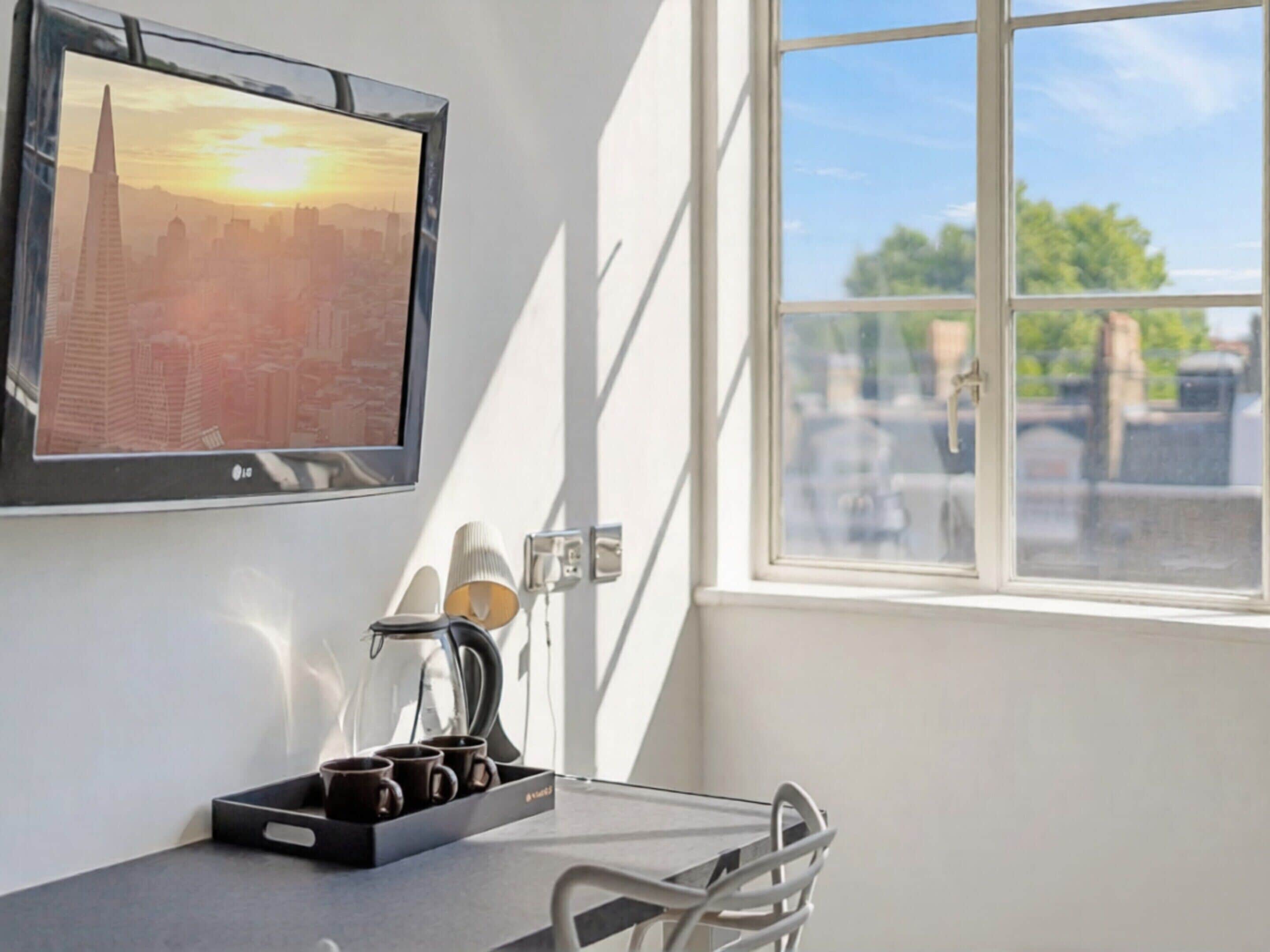 Une chambre avec vue sur la ville, une table avec une machine à café et un plateau avec des tasses.
