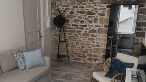 Een woonkamer met een stenen muur, een bank, een salontafel, een stoel en een televisie.