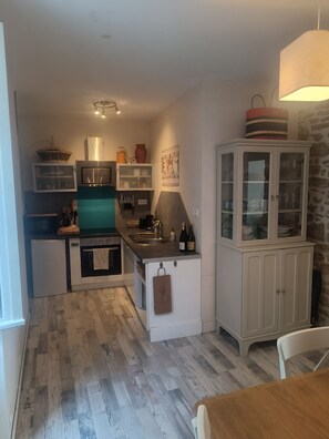 Eine kompakte Küche mit Mikrowelle, Backofen und Spüle. Es gibt einen Schrank mit Glastüren und einen kleinen Kühlschrank.