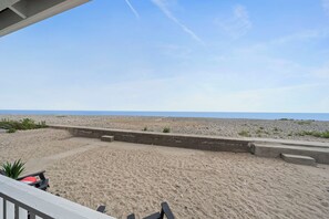 En strand med en betongbarriär, ett sandområde och utsikt över havet.