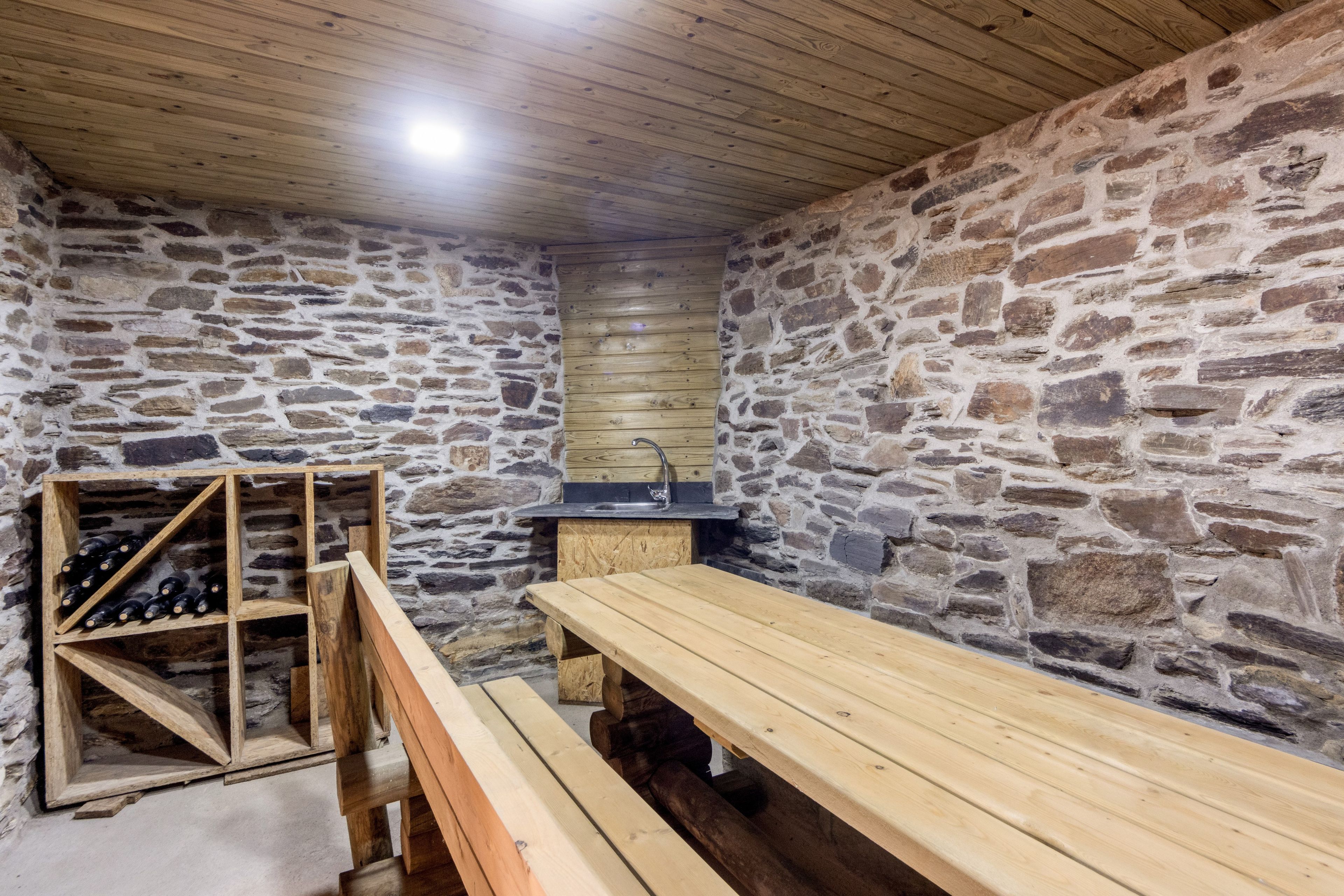 A stone-walled room with a wooden bench and a wine rack.