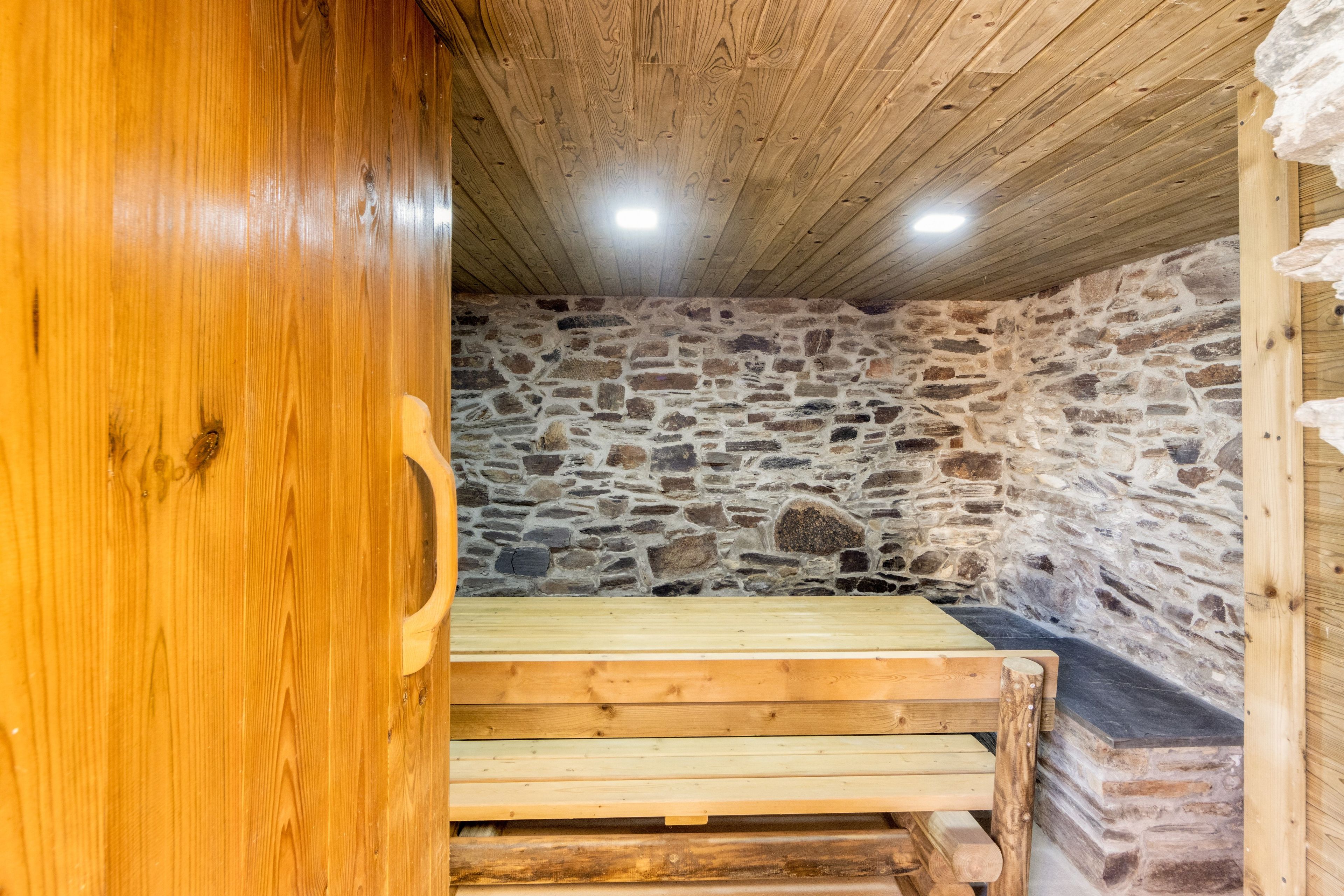 Un banco de madera en una habitación de paredes de piedra y techo inclinado.