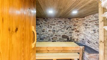 Un banco de madera en una habitación de paredes de piedra y techo inclinado.
