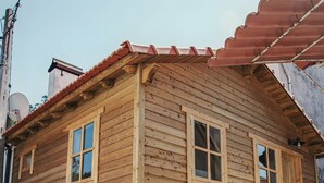 Um edifício de madeira com base de pedra, telhado de telhas vermelhas e uma placa indicando que é uma instalação de TV e sauna.