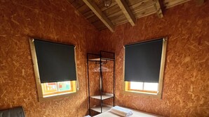 Um quarto com uma cama, um banco, uma prateleira e uma janela.