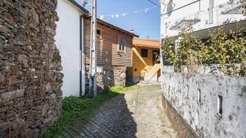 Un estrecho callejón adoquinado con muros de piedra a un lado y un edificio con fachada amarilla al otro.