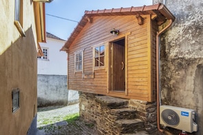 A wooden house with a stone foundation, a visible door, and a window. - Holiday Home 'Casa da Avó Deolinda' with Mountain View in Grijó (Gafanhão)