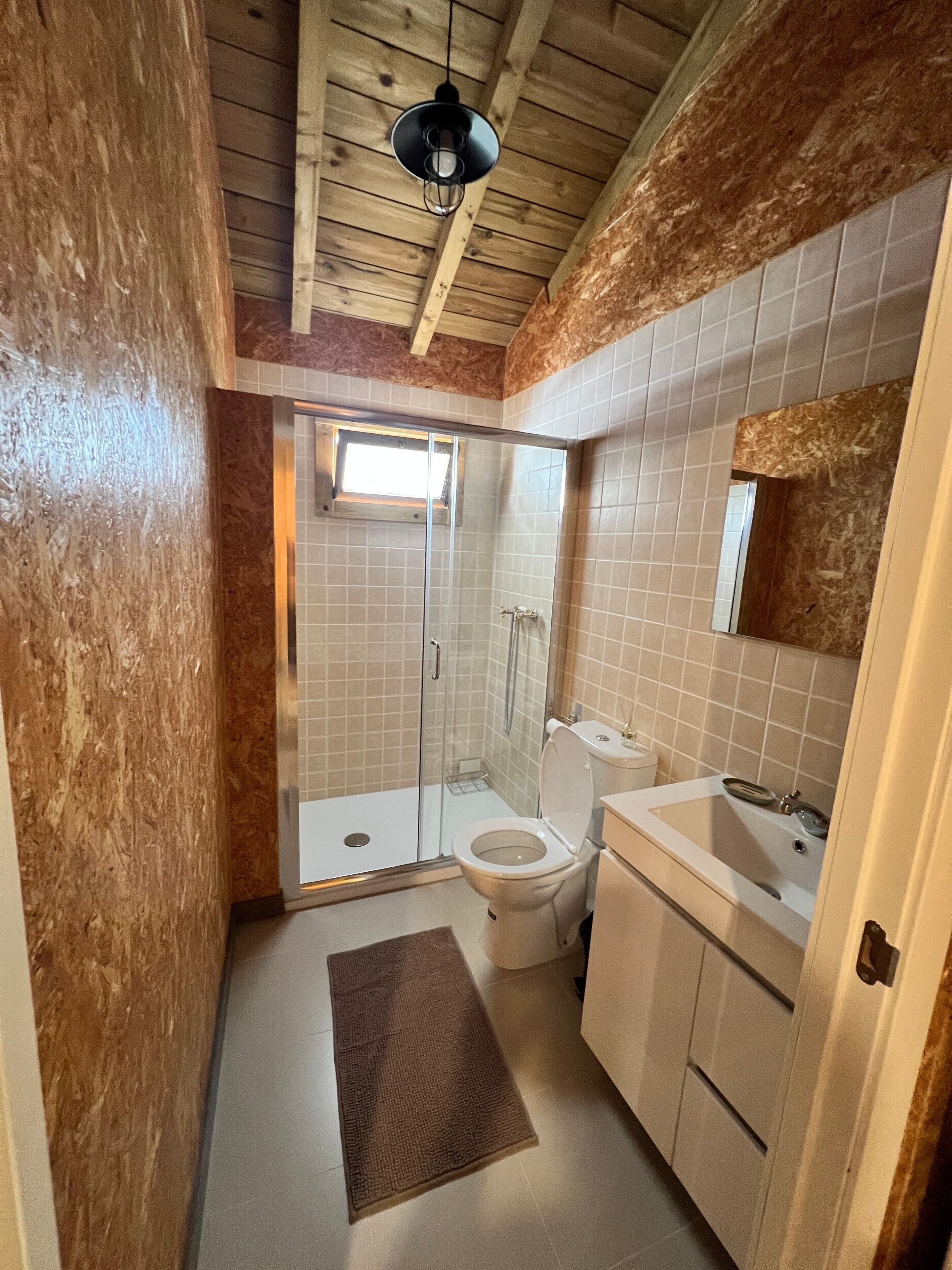 Une salle de bain avec une douche, des toilettes, un lavabo et une fenêtre.