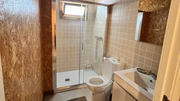 Une salle de bain avec une douche, des toilettes, un lavabo et une fenêtre.