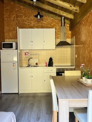 A compact kitchen with white cabinets, a microwave, a coffee maker, and a sink.