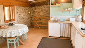 Una cocina acogedora con pared de piedra, techo de madera y un lavamanos pequeño.
