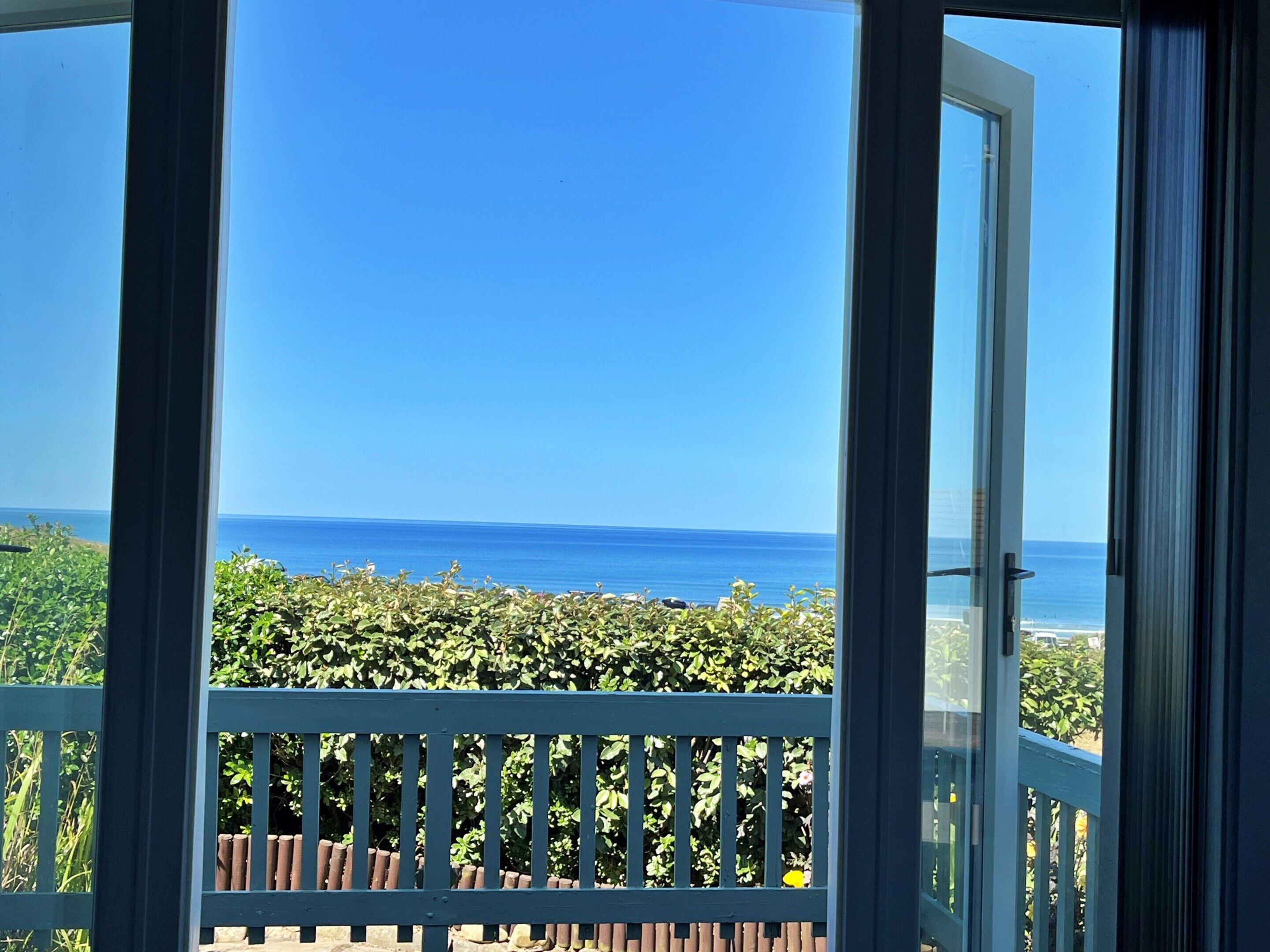 Een balkon met uitzicht op de oceaan en een heldere lucht.