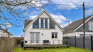 A two-story house with a sloped roof, a fenced backyard, and a clear sky. - Stunning Broad Haven Beach House (Newquay)