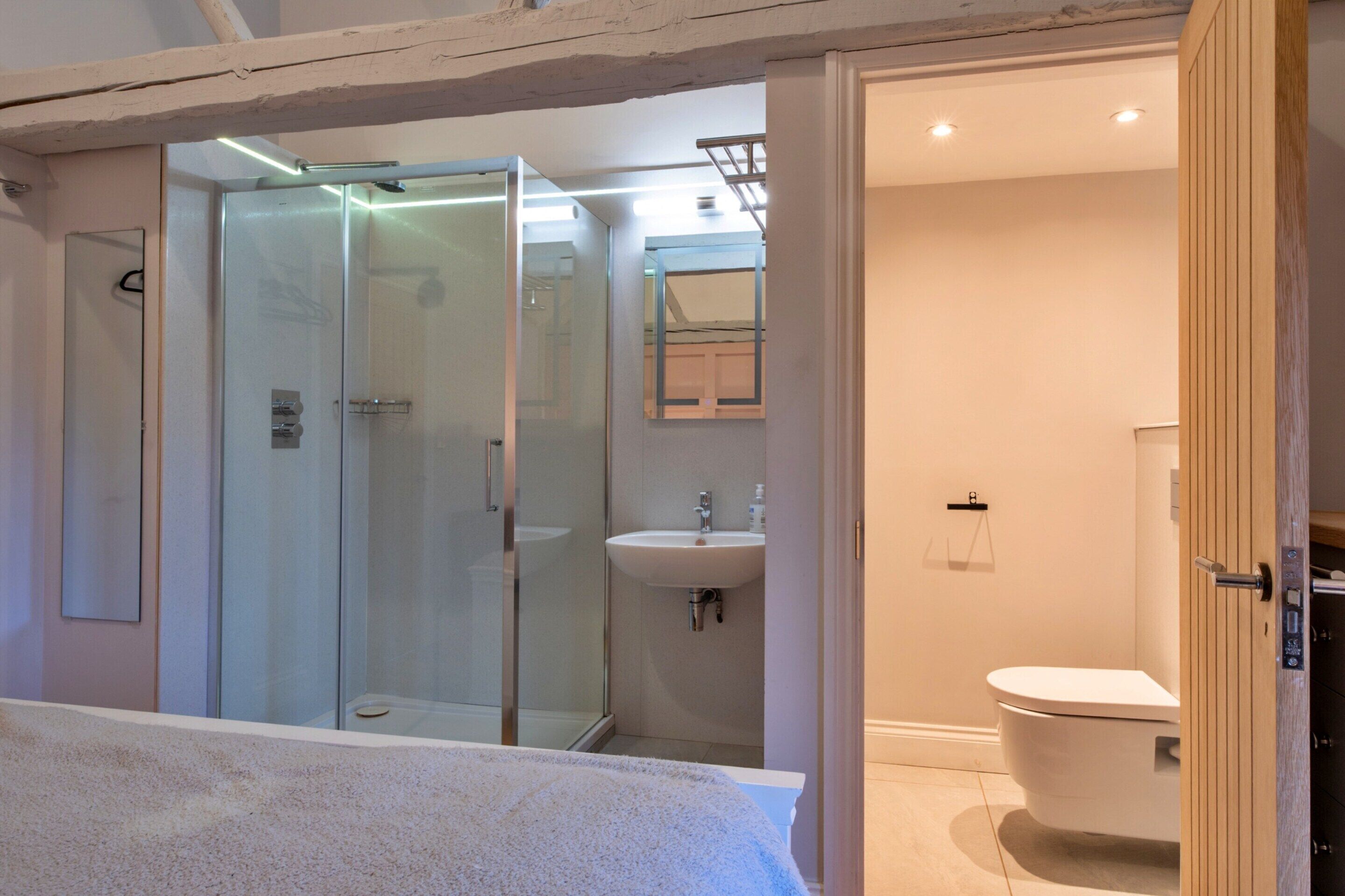 Un baño moderno con cabina de ducha de vidrio, un lavabo y un inodoro.