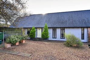 A single-story house with a dark shingled roof, a front door, and a small porch area. - Charming Cottage for 4 in Dorset (Wimborne)