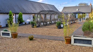 A courtyard with a pergola, potted plants, and a gravel pathway. - Charming Cottage for 4 in Dorset (Wimborne)