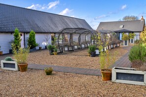 Ein Innenhof mit einer Pergola, Blumentöpfen und einem Kiesweg.