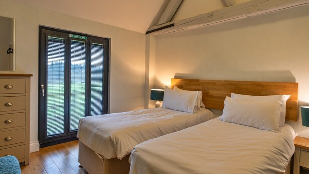 A bedroom with two beds, a dresser, and a door marked 'Fire exit only.' - Charming Cottage for 4 in Dorset (Wimborne)
