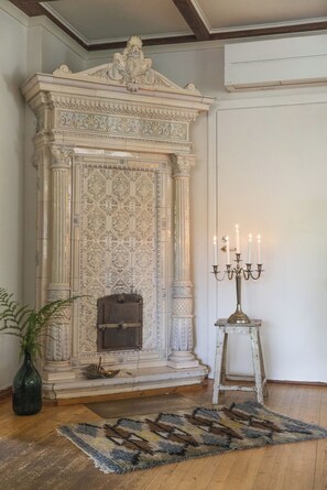 Una habitación con chimenea, un candelabro y una alfombra estampada.