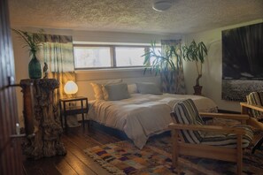 A cozy bedroom with a bed, a chair, a nightstand, a lamp, and several potted plants. - Private Historic Lakeside Villa, 30 Min from Helsinki (Sipoo)