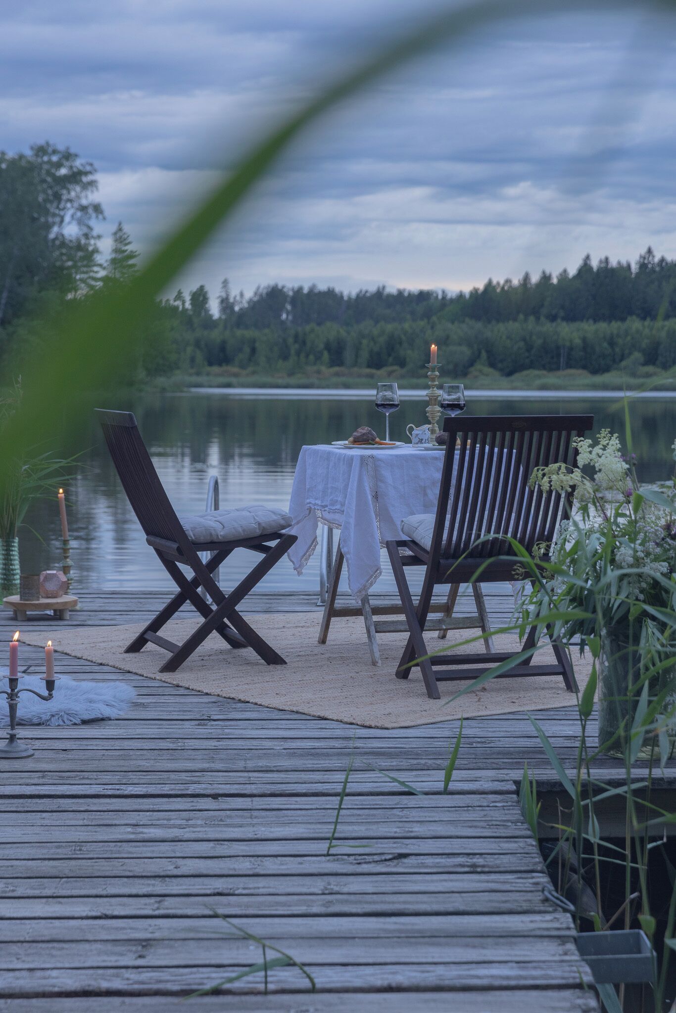 En træterrasse med et bord og stole med udsigt over en sø.