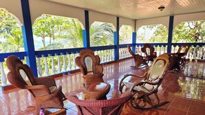 A covered outdoor seating area with wicker furniture and a tiled floor.