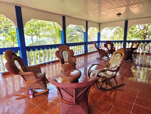 A covered outdoor seating area with wicker furniture and a tiled floor.