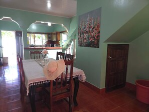 A dining area with a table set for two, a staircase, and a kitchen in the background.