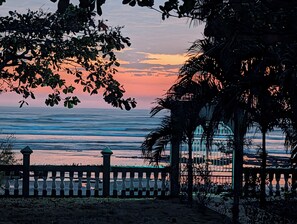 A coastal sunset view with a gazebo and a fence.
