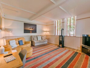 Una sala de estar con sofá, televisor, chimenea y un amplio ventanal.