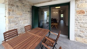 A wooden table and chairs in a room with stone walls and a sliding glass door leading to another space. - Two Bedroom Sea View Apartment Marisol (Mrljane)