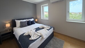 A modern bedroom with a bed, bedside lamps, a window, and an air conditioning unit. - Two Bedroom Sea View Apartment Marisol (Mrljane)
