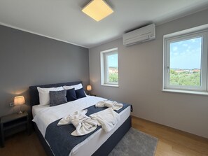 A modern bedroom with a bed, bedside lamps, a window, and an air conditioning unit. - Two Bedroom Sea View Apartment Marisol (Mrljane)