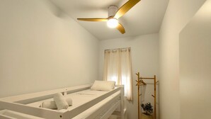 A single-bed room with a ceiling fan, a window with curtains, and a wooden coat rack with a potted plant. - Travel Habitat Marchalenes Apartment - 3 BedRooms (Valencia)