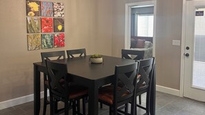 A dining area with a dark wooden table and chairs, a ceiling light fixture, and a wall-mounted artwork. - Desert Oasis route 66 (Kingman)