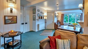 A cozy interior with a dining area, a sofa, and a table with a vase of flowers. - Historic Cornish Valley Cottage for 5 (Bude)