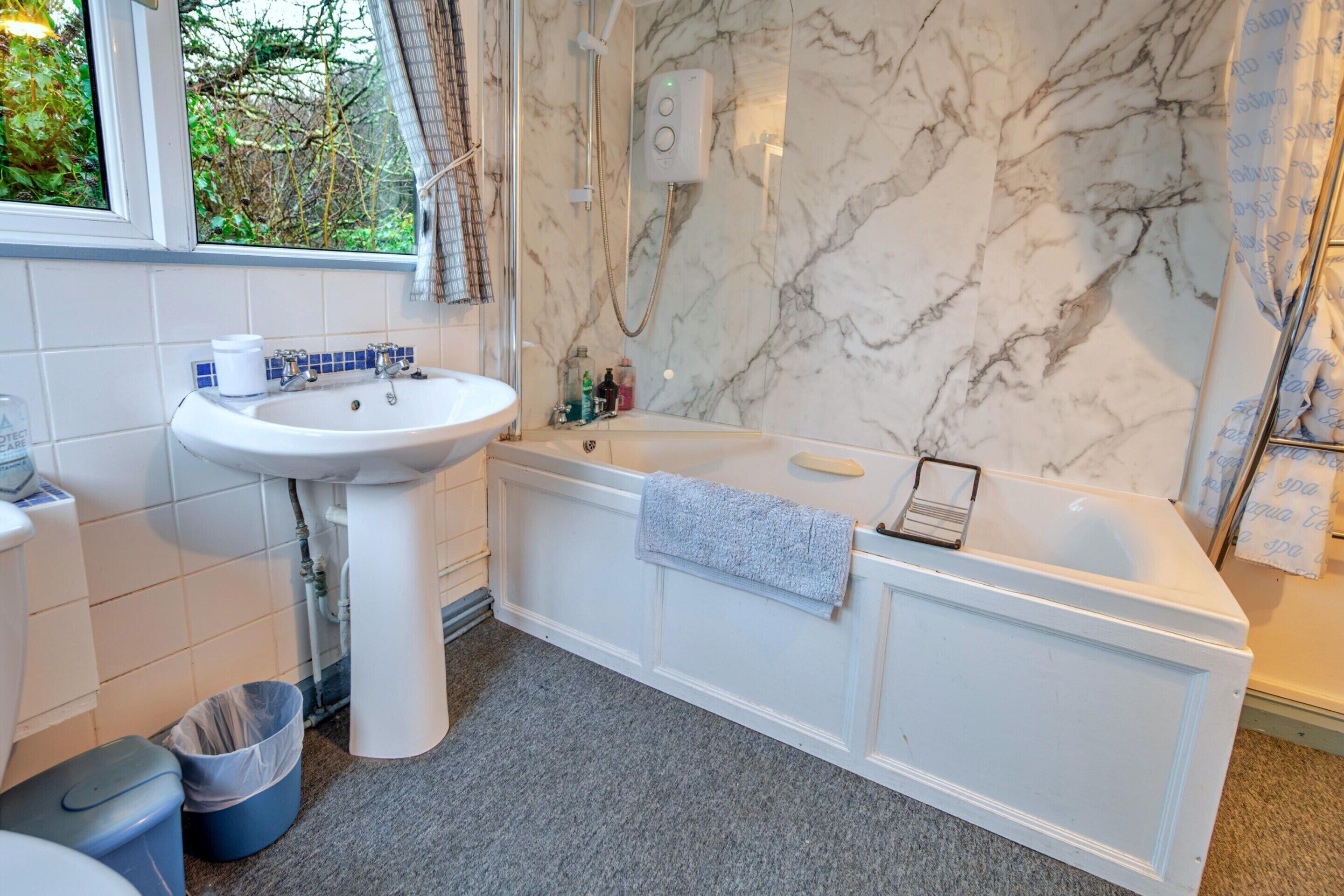 Une salle de bain avec un lavabo blanc, une baignoire et un espace douche.