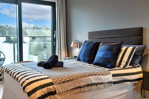 Ein Hotelzimmer mit einem großen Bett, Blick auf die Stadt und einem Vorhangfenster.