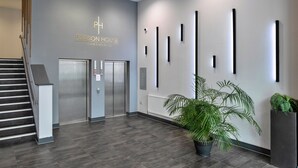 A modern interior with a staircase, elevators, and a reception area with a sign for 'PEIRSON HOUSE APARTMENTS'. - Modern Plymouth Apartment Near The Hoe (Plymouth)