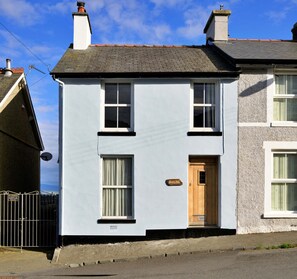 A two-story house with a white exterior, a wooden door, and a visible chimney. - Amazing Home With Cardigan Bay Views (Criccieth)