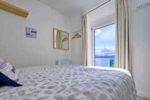 A bedroom with a bed, a mirror, a radiator, and a view of the sea. - Amazing Home With Cardigan Bay Views (Criccieth)